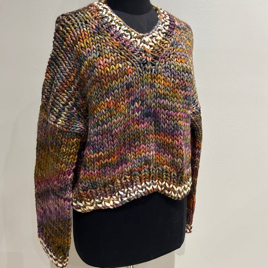 Multicolored knitted pullover on a mannequin head against a plain background