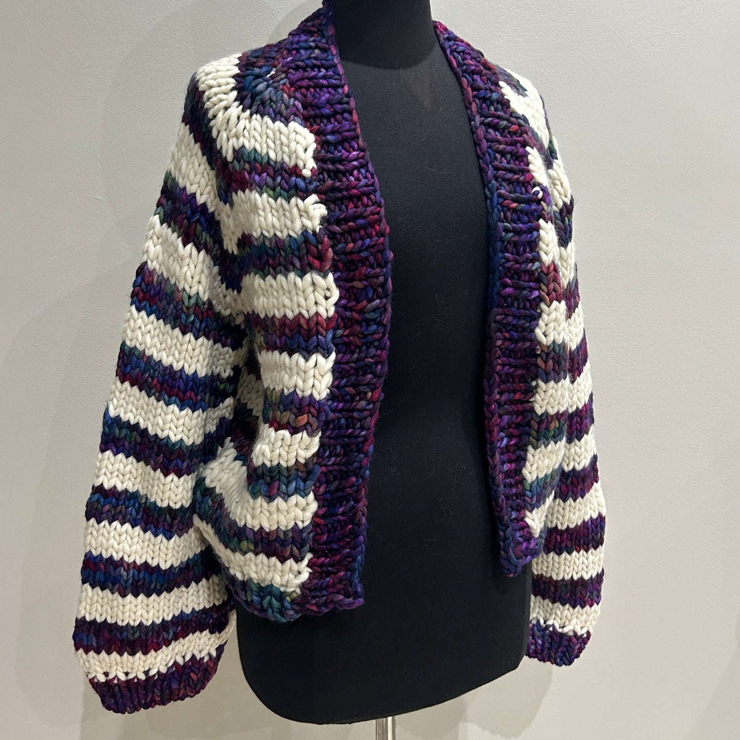 Striped knitted cardigan on a mannequin head against a neutral background